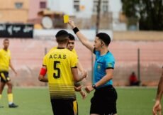 The referee shows a yellow card during a soccer game.