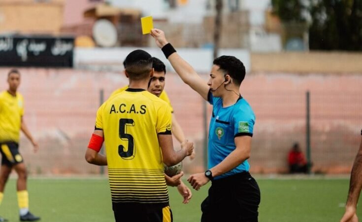 The referee shows a yellow card during a soccer game.